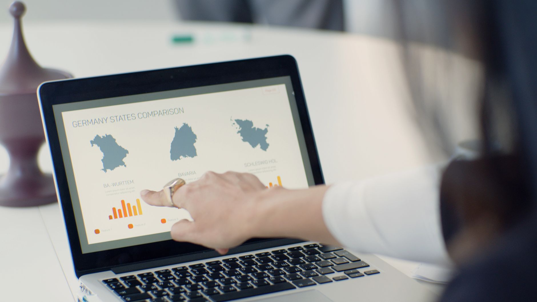 Hand zeigt auf Finanzauswertung mit Diagrammen auf einem Laptop